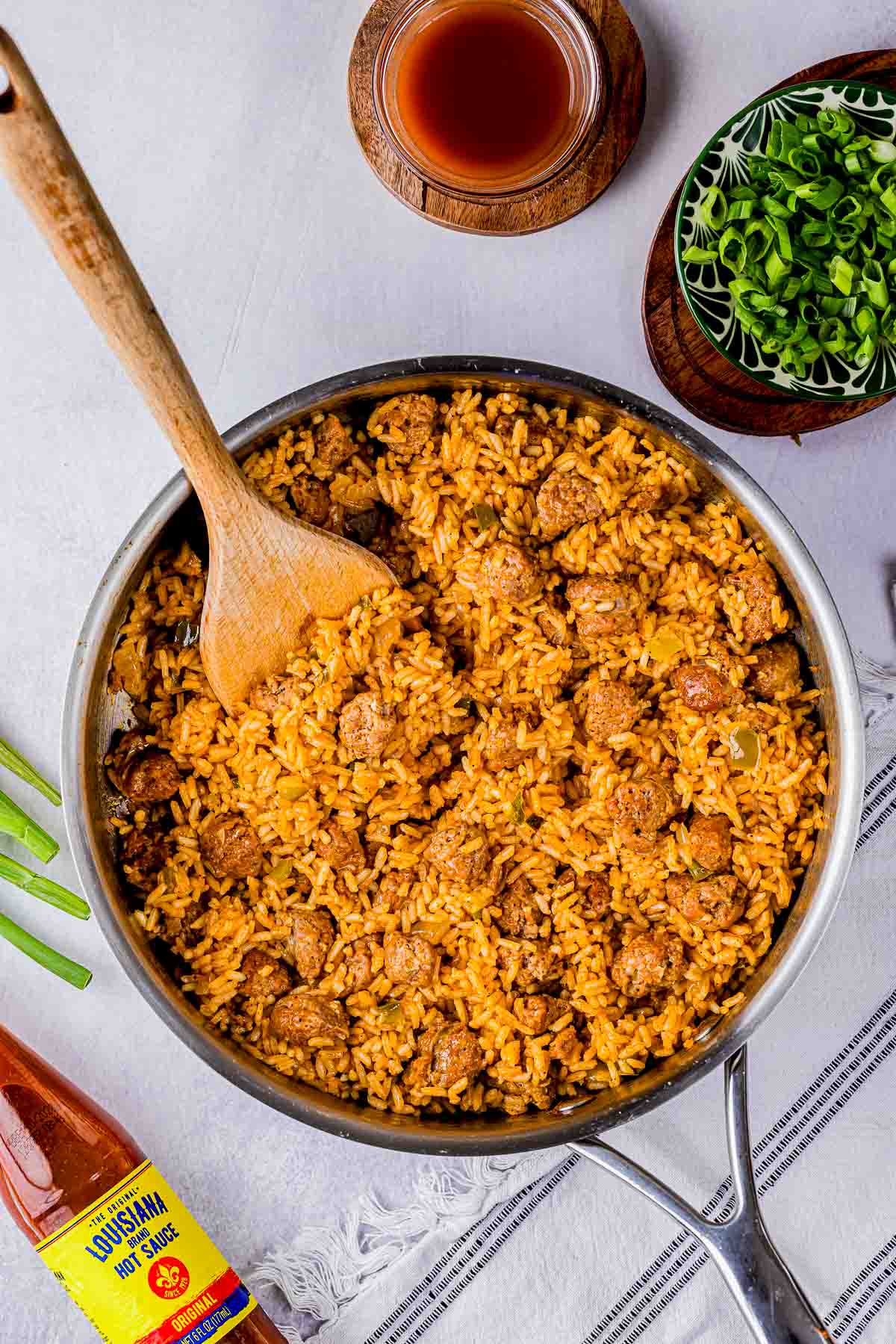 a skillet of yellow colored rice and a wooden spoon.