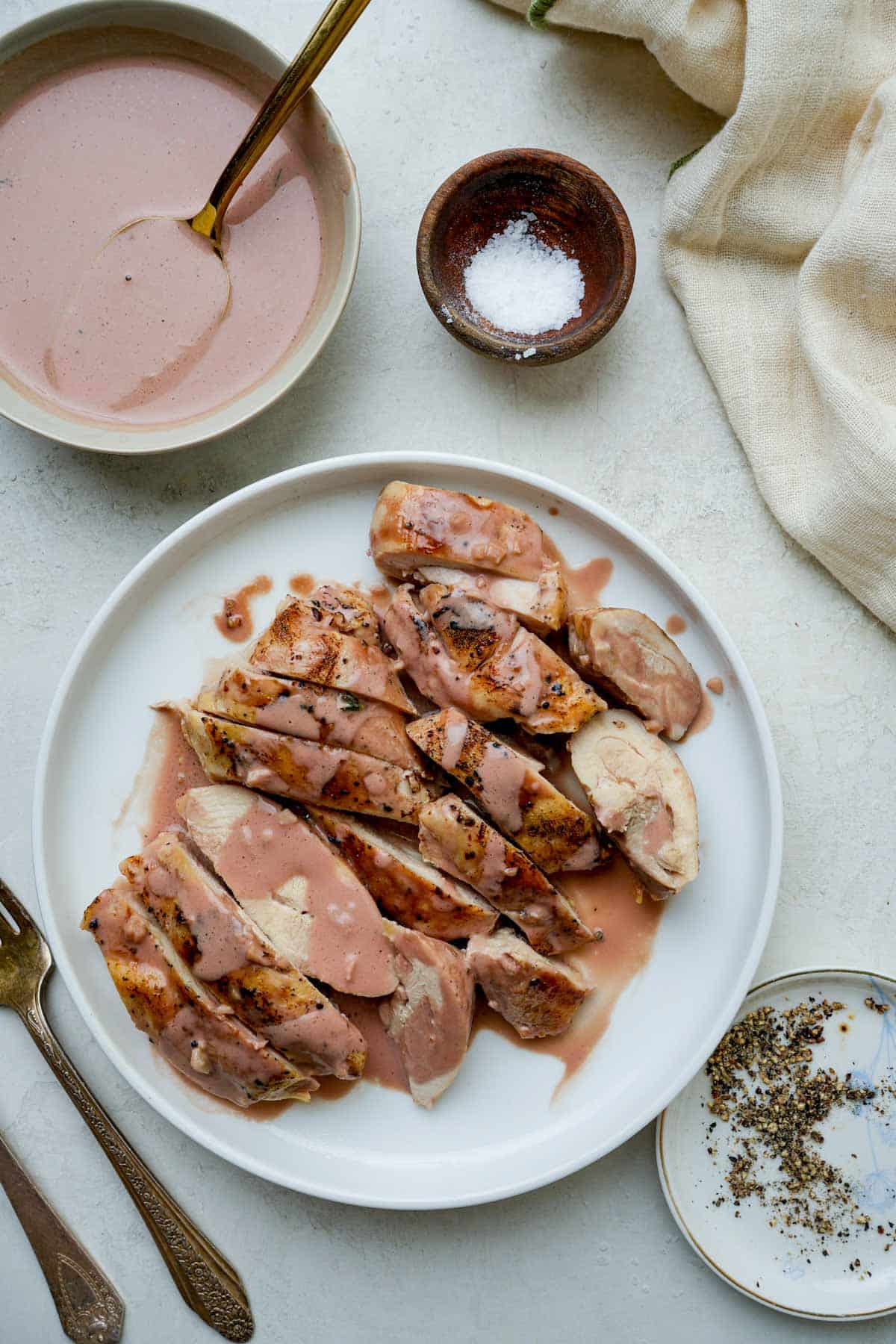 sliced chicken on a plate with sauce on top.