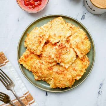 a plate of fried ravioli with marinara on the side.