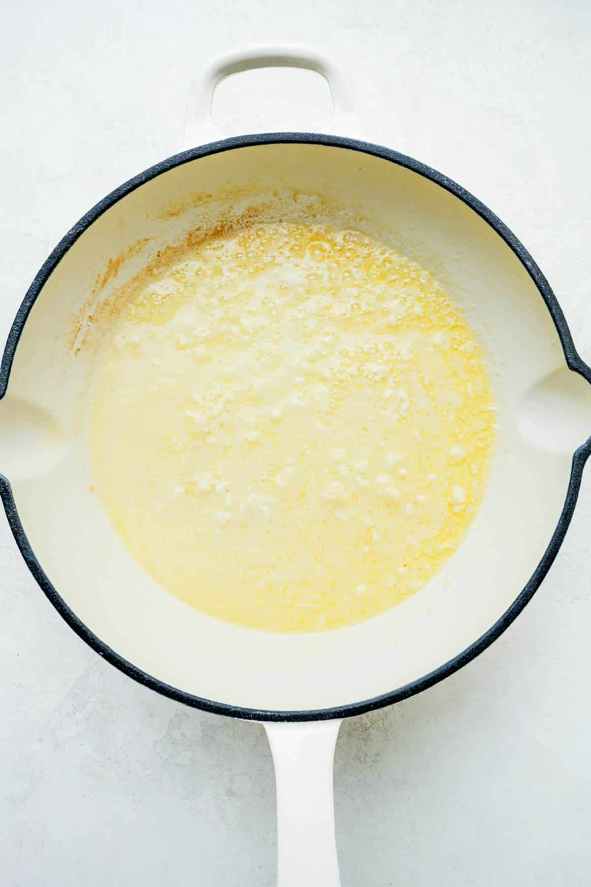 butter and onions cooking in a skillet.