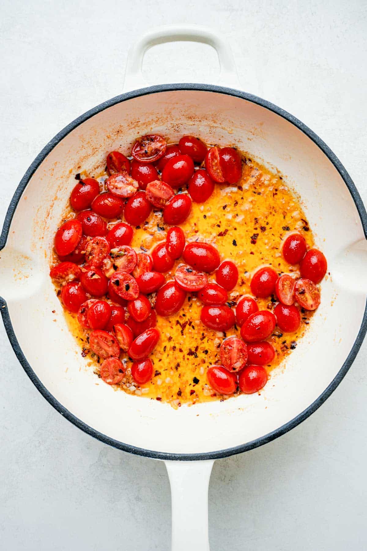 cherry tomatoes and butter cooking in a skillet.