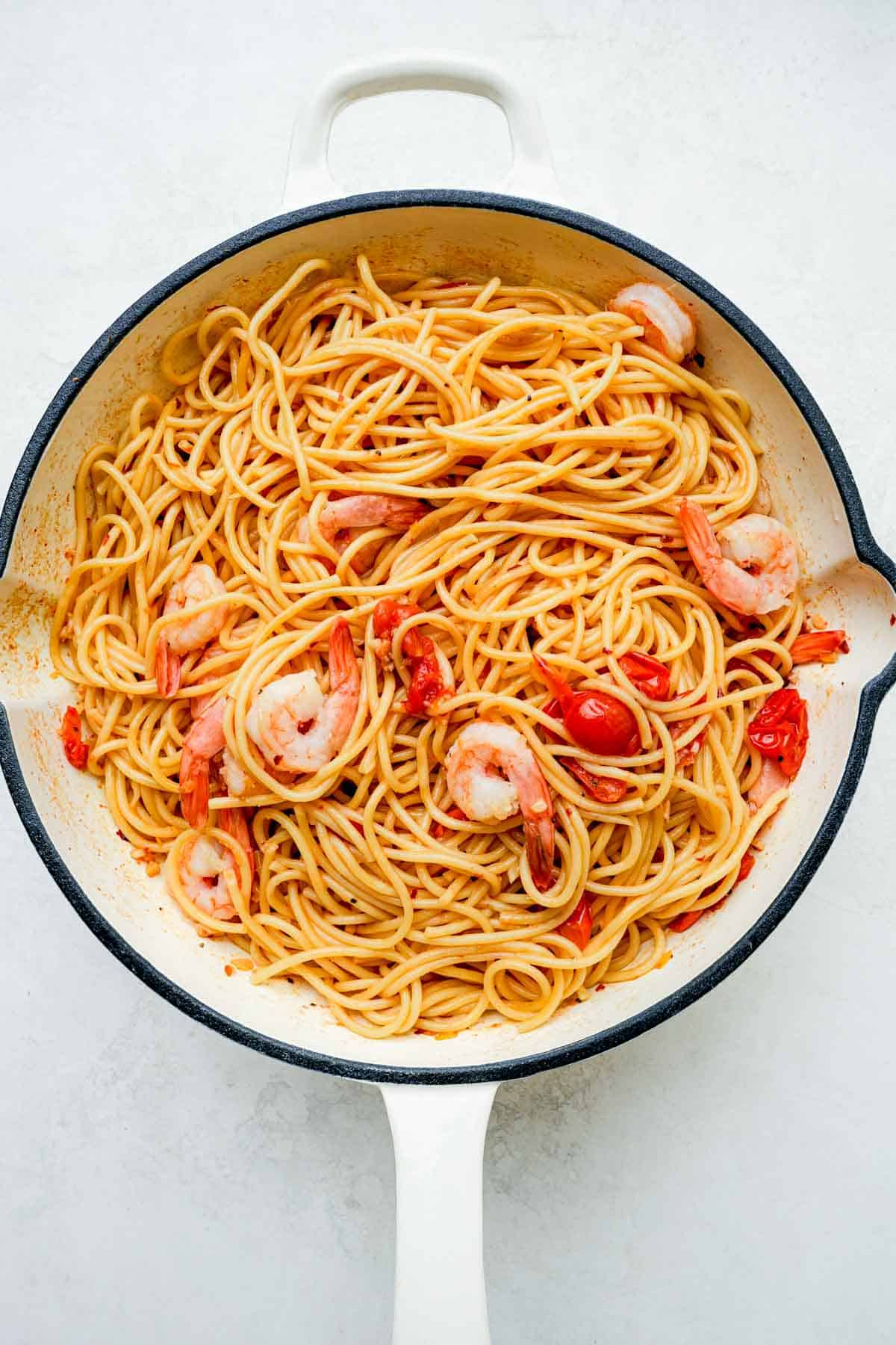 pasta mixed with tomatoes and sauce and shrimp in a skillet.