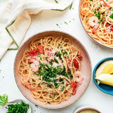 2 bowls of pasta with shrimp and parsley on top.