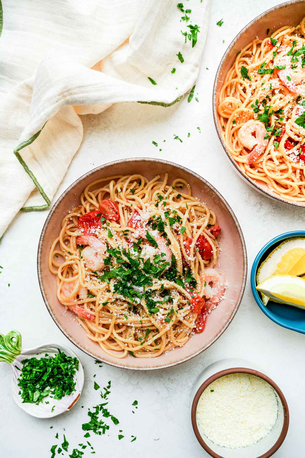 2 bowls of pasta with shrimp and parsley on top.