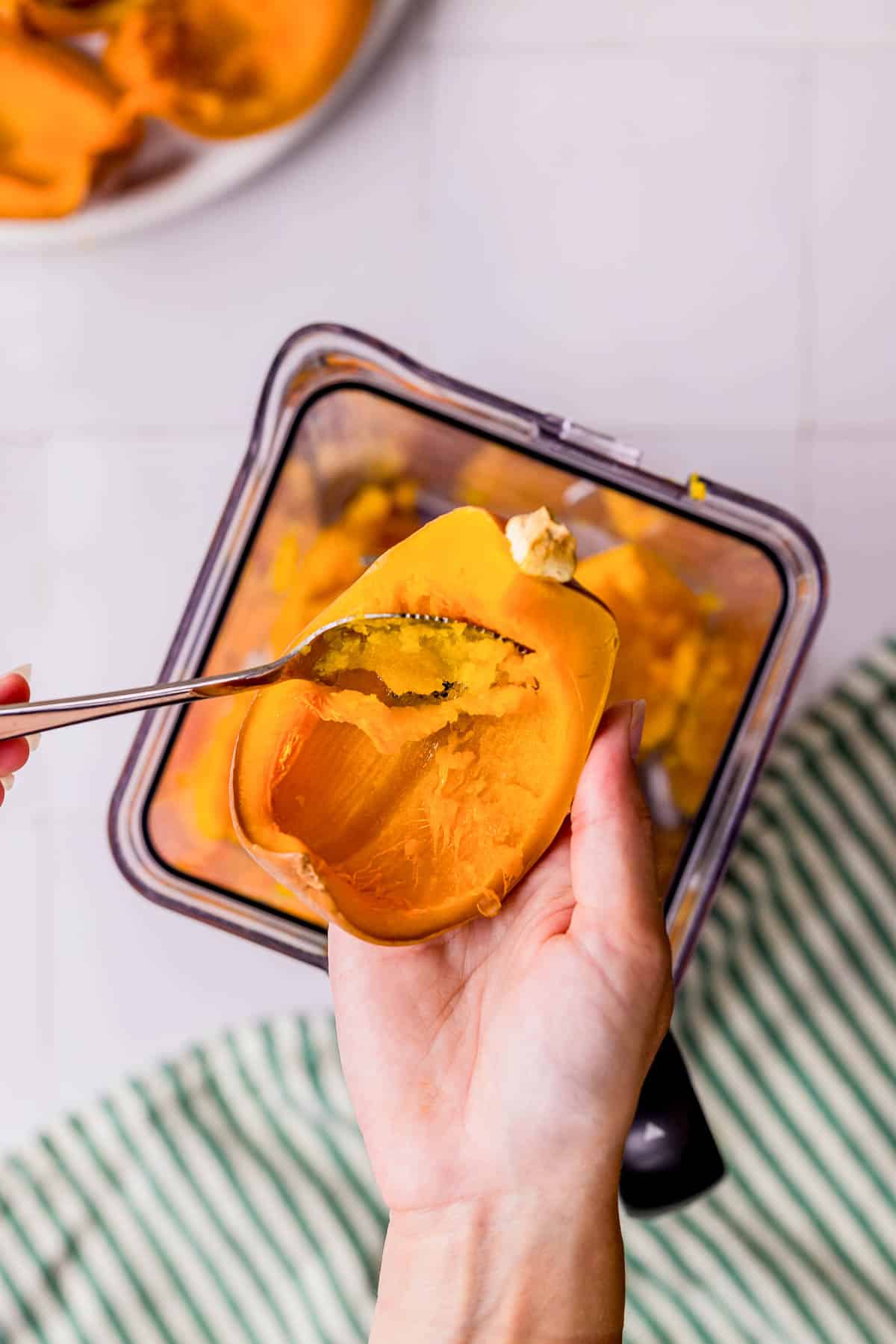 scooping pumpkin flesh out of a piece of pumpkin.