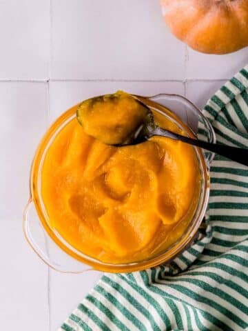 a bowl of pumpkin puree with a spoon in it.