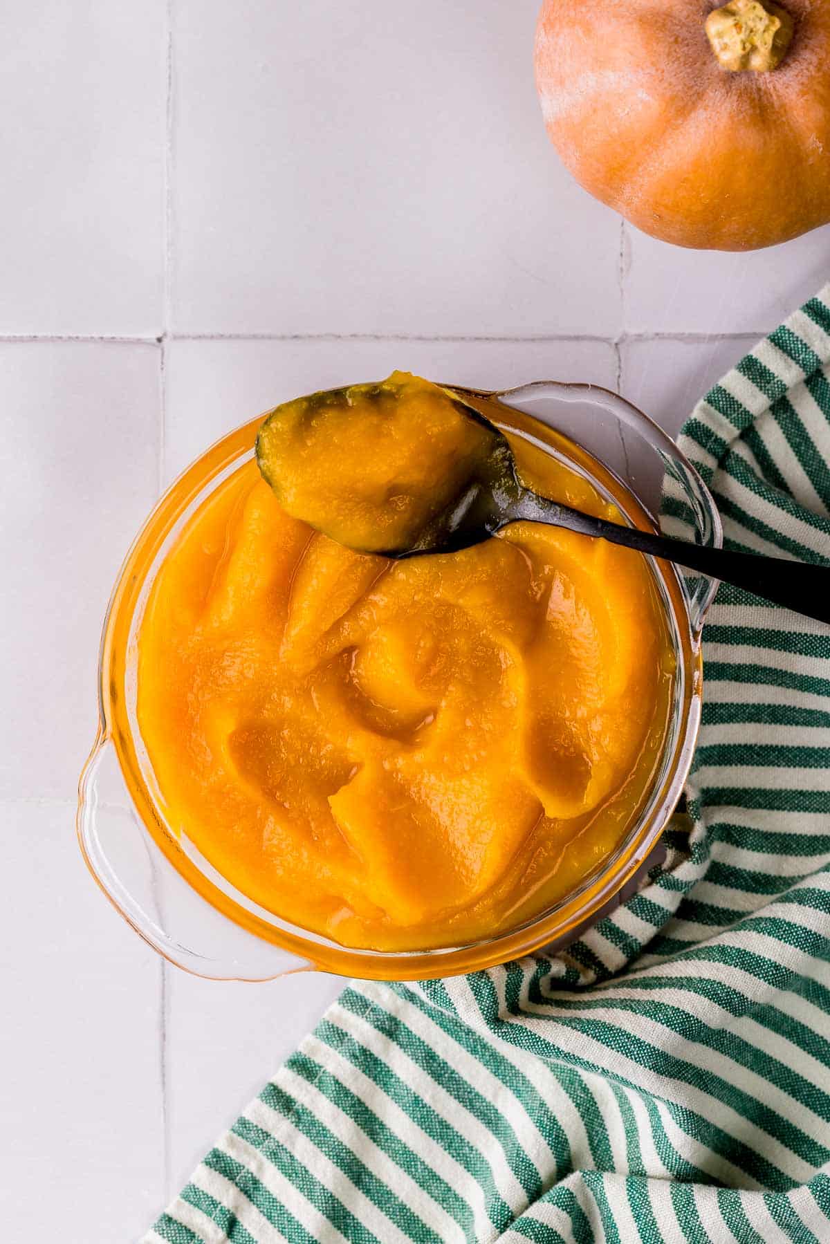 a bowl of pumpkin puree with a spoon in it. 