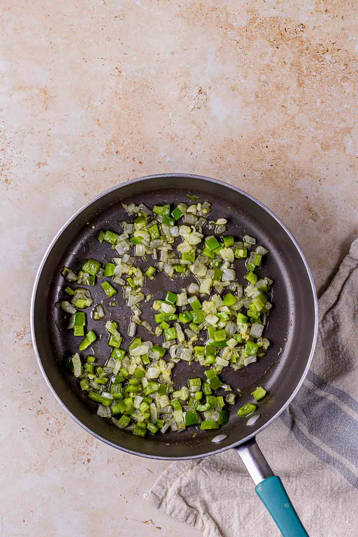 green peppers and onions cooking in a skillet.