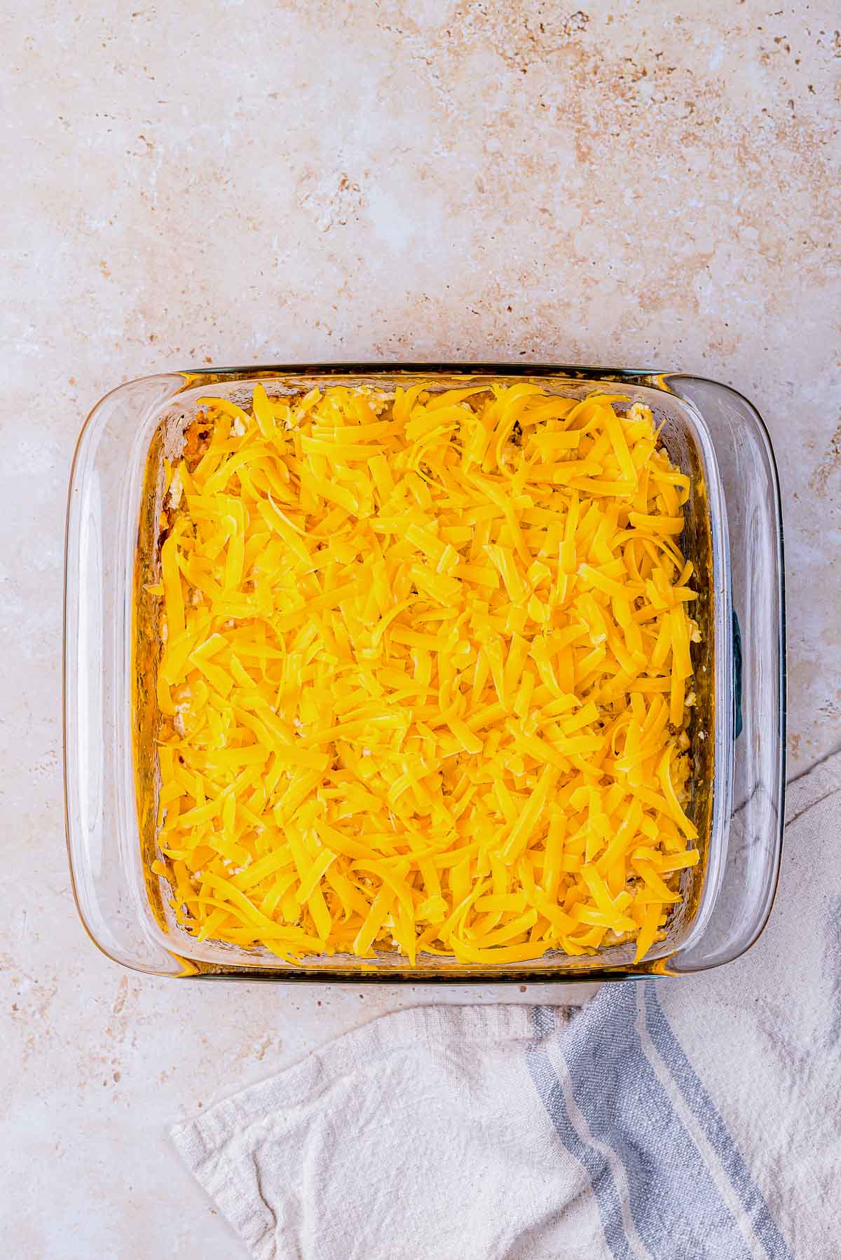 shredded cheddar cheese spread on top of a baking dish.