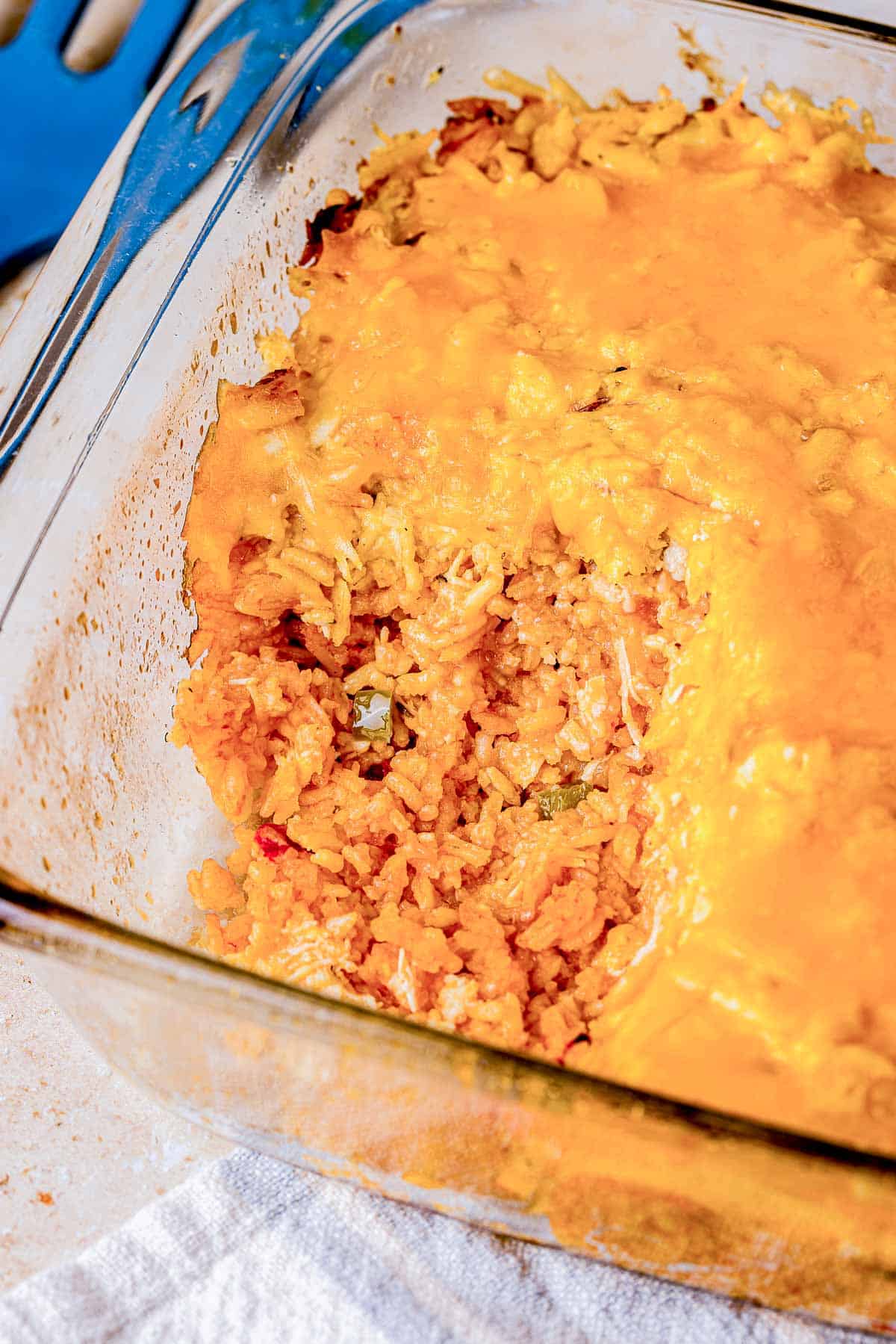 a casserole dish of rice and cheese with a spoonful taking out.