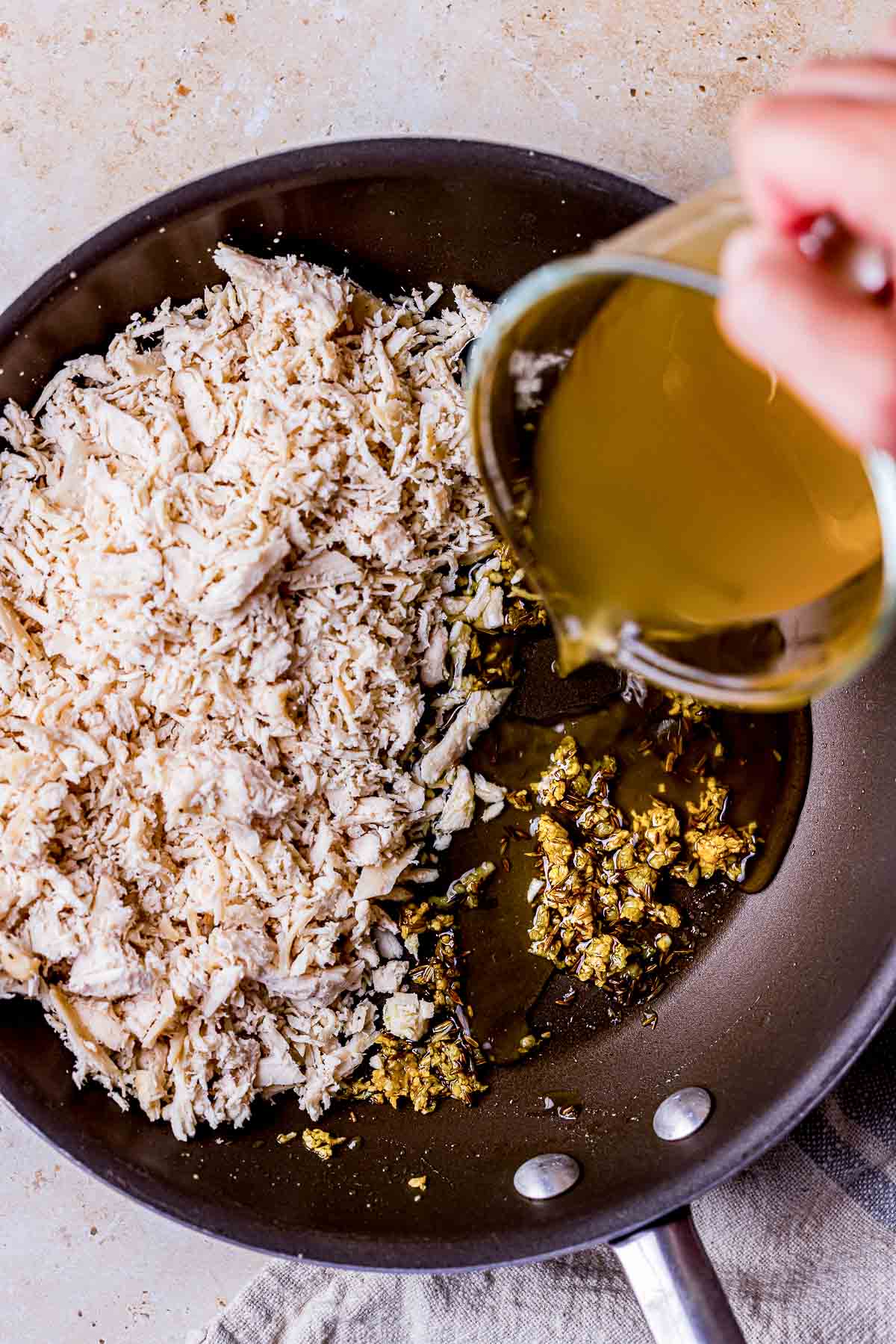 broth poured into a skillet of shredded chicken.