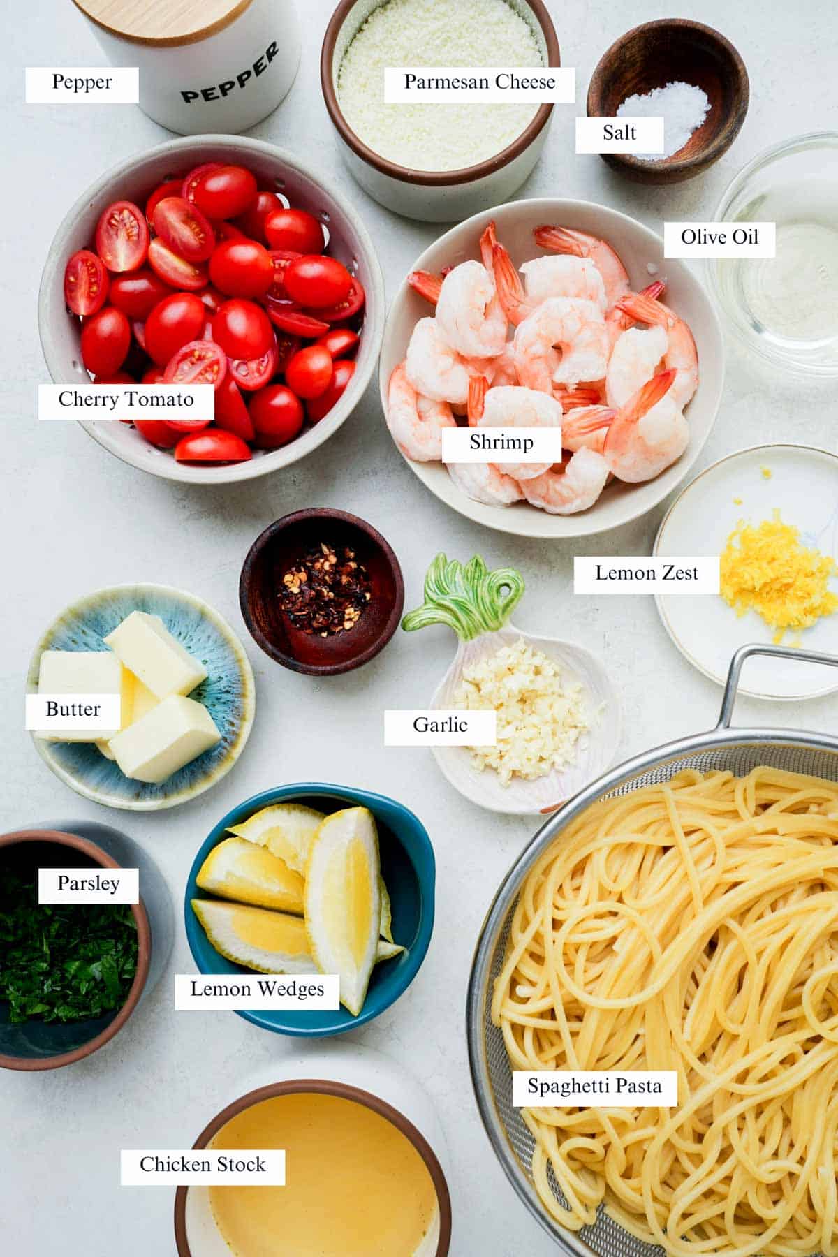 ingredients for butter garlic shrimp spaghetti on a white surface with labels.