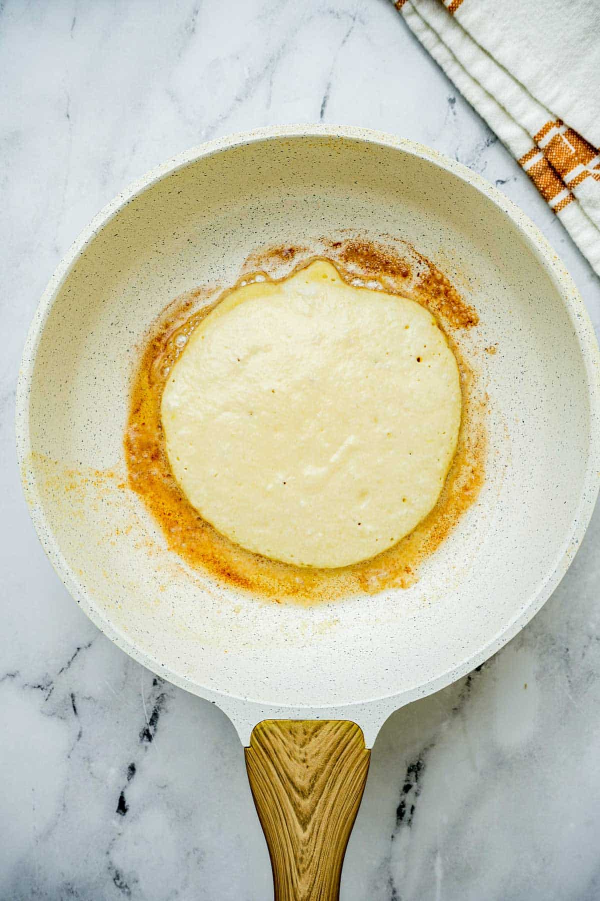 raw pancake batter being cooked in a skillet.