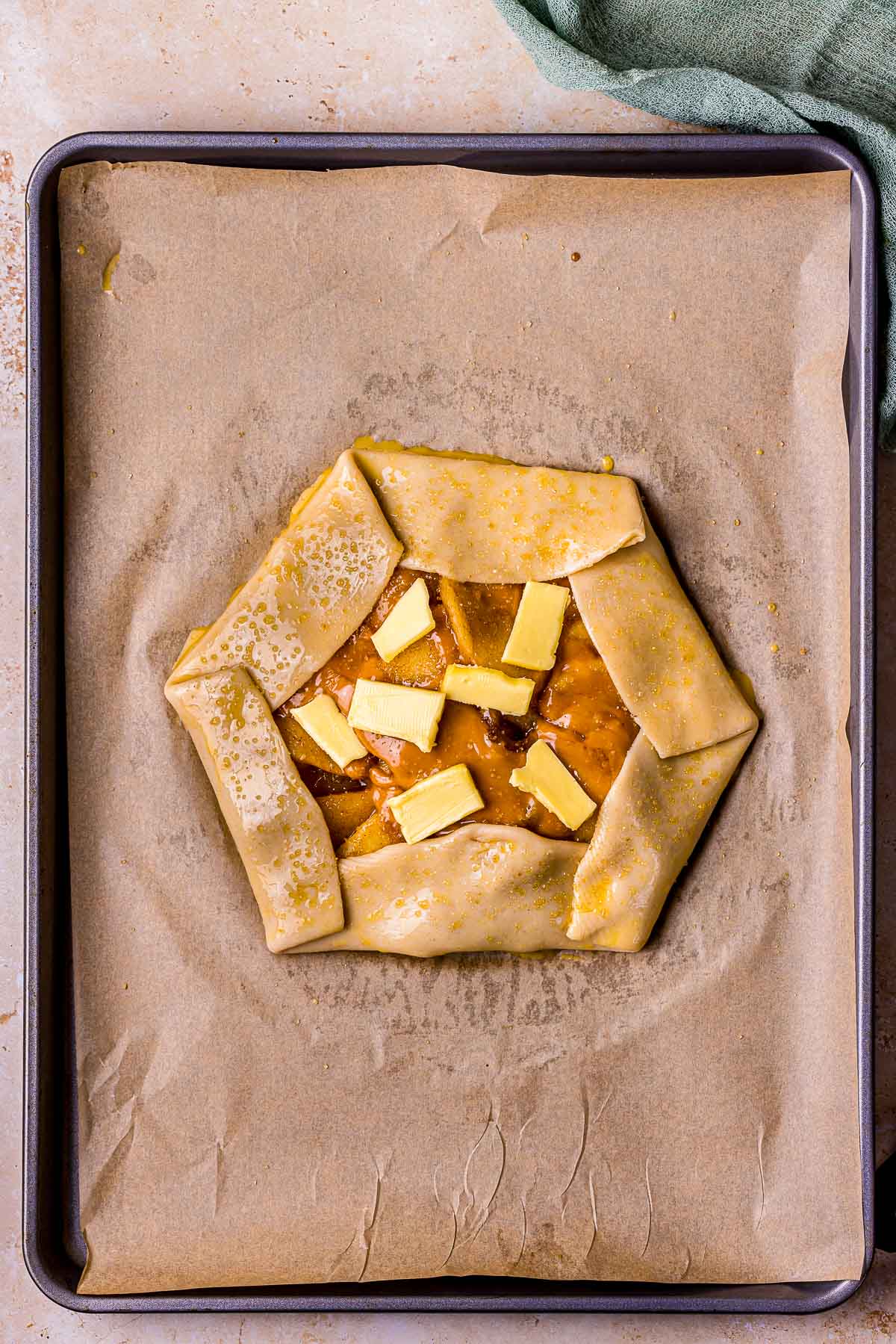 pieces of cold butter on top of uncooked apple galette.