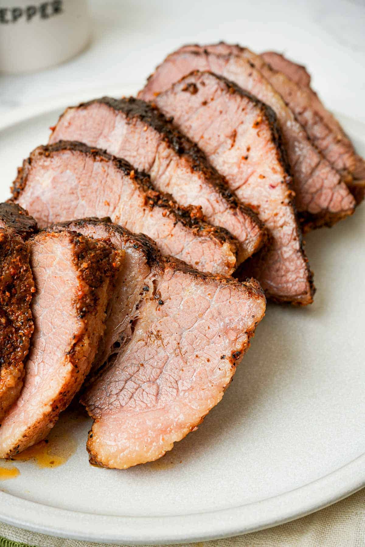 slices of sous vide brisket on a white plate.