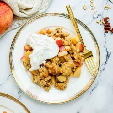 apple crisp on a plate with whipped cream.