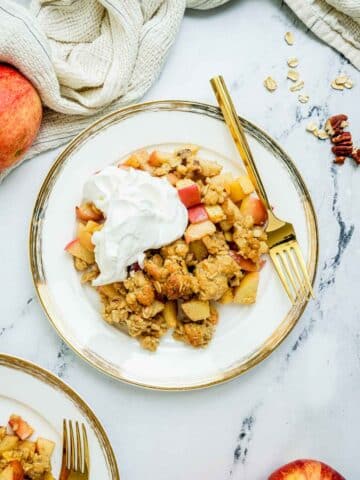 apple crisp on a plate with whipped cream.