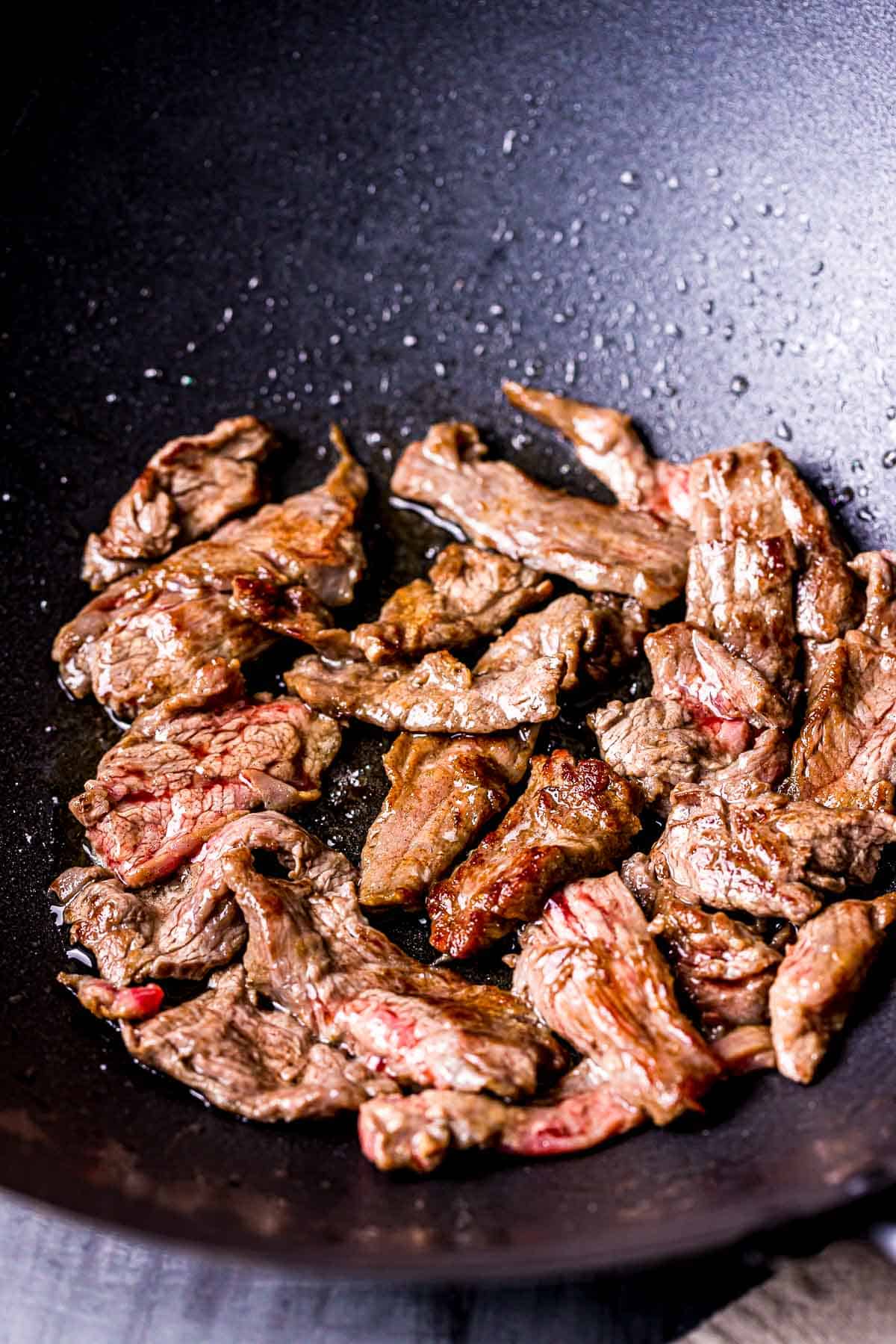 strips of beef browning in a wok.