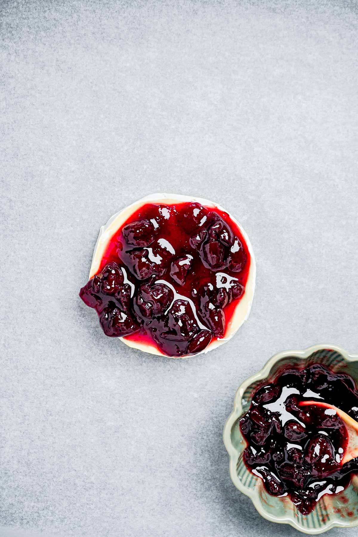 round of brie with cranberries on top.