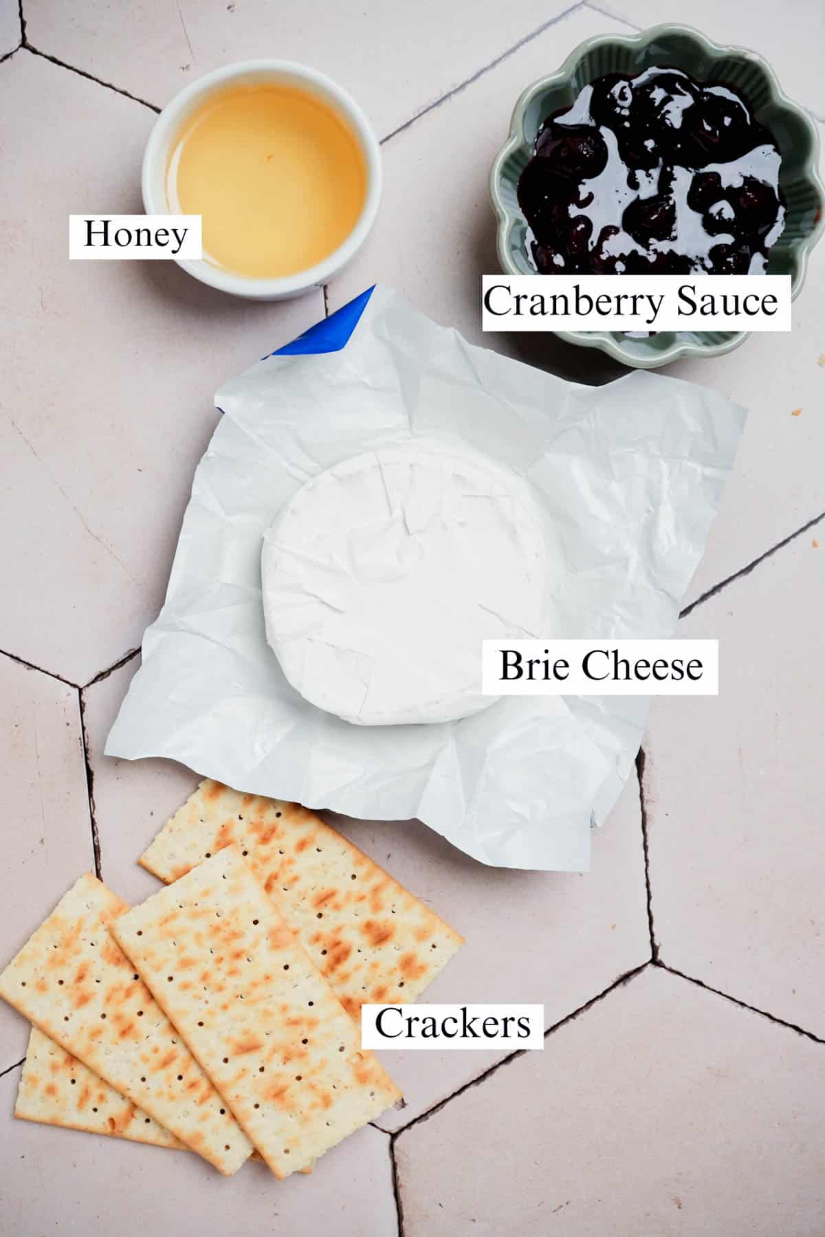 ingredients for cranberry baked brie on a tile surface.