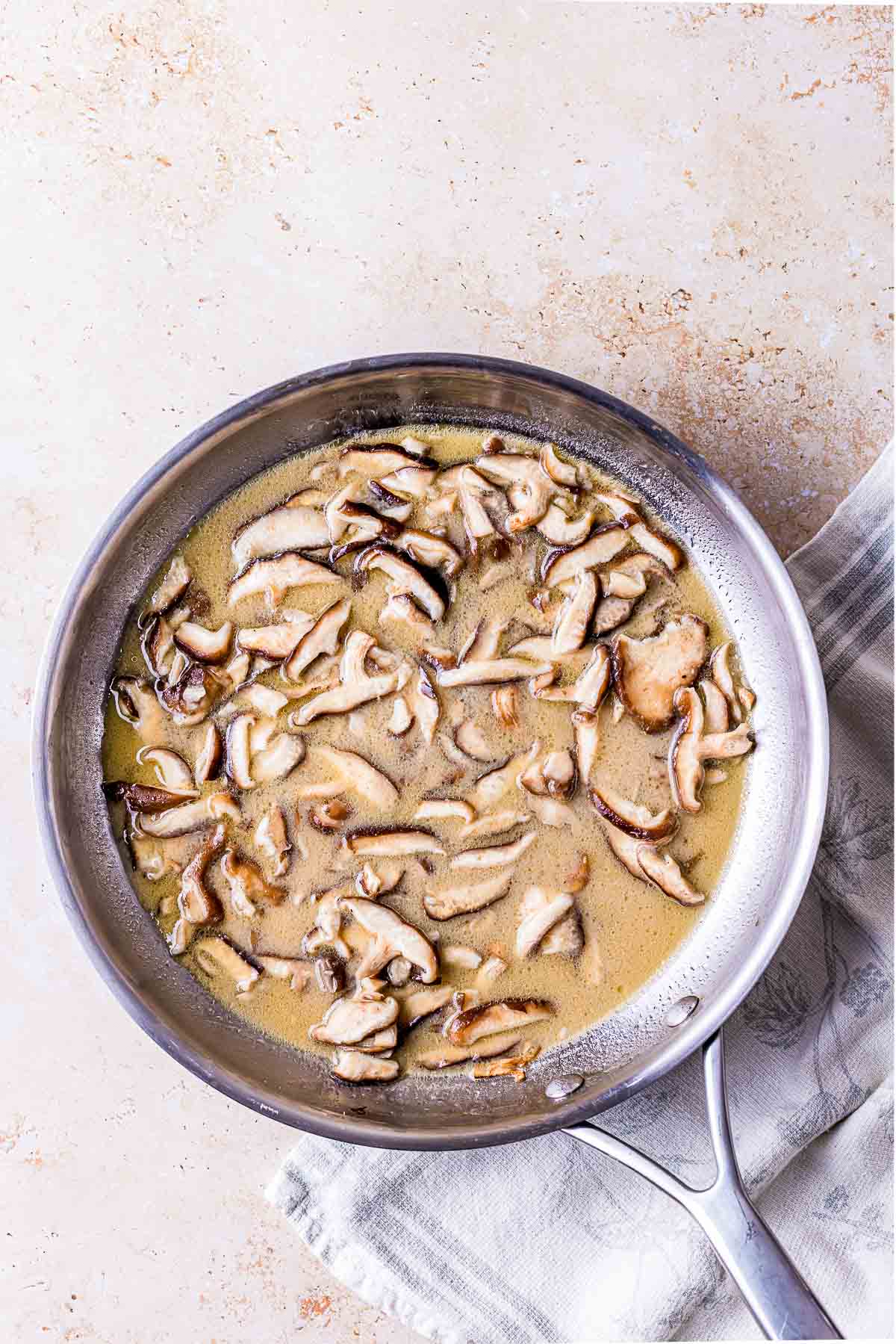 mushrooms cooking in liquid in a skillet.