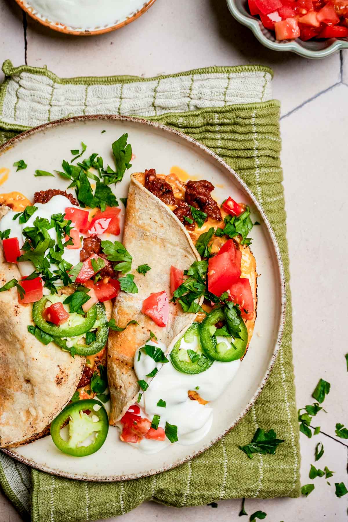 garnished tacos on a plate with sour cream.