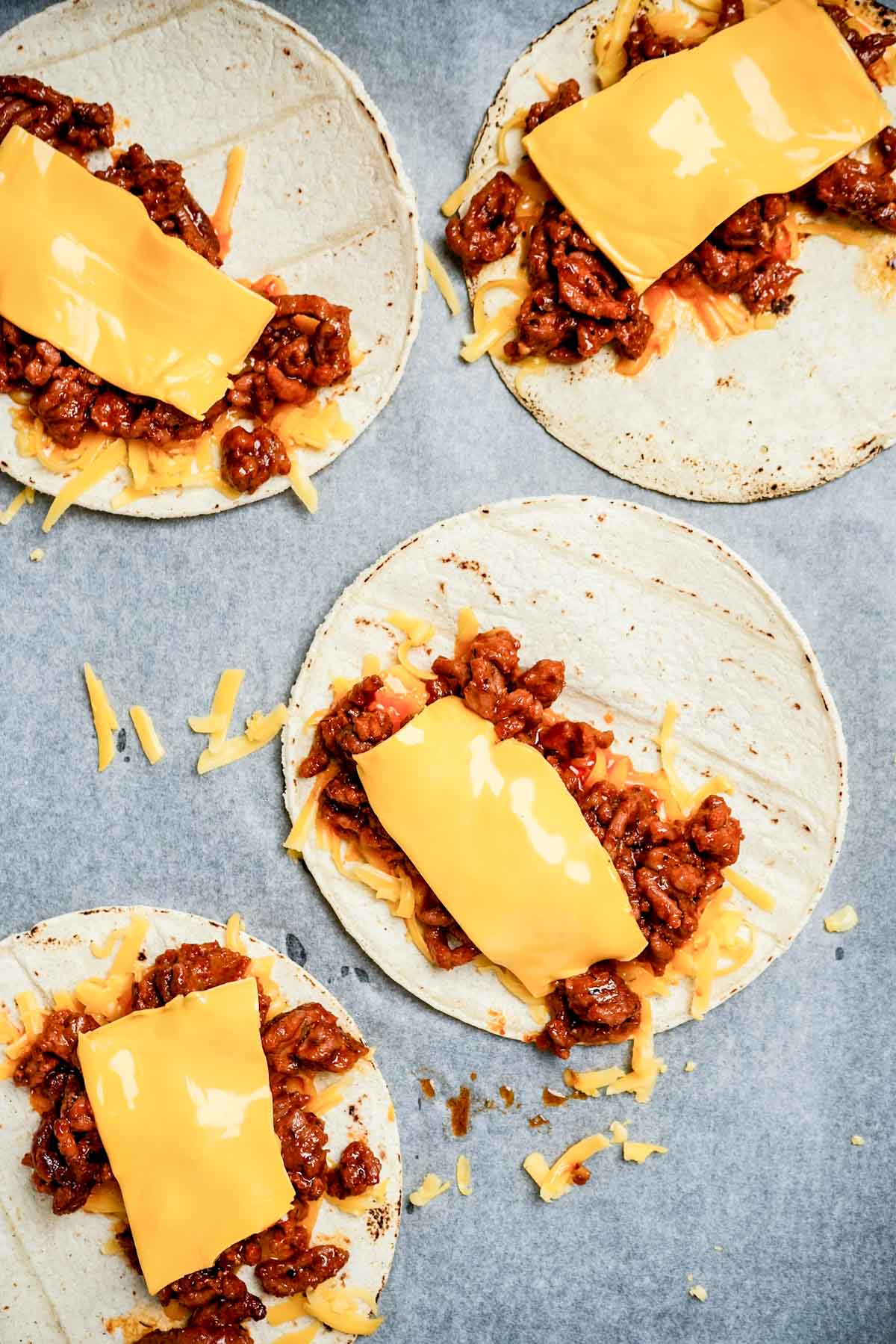 melted yellow cheese and ground beef on corn tortillas.