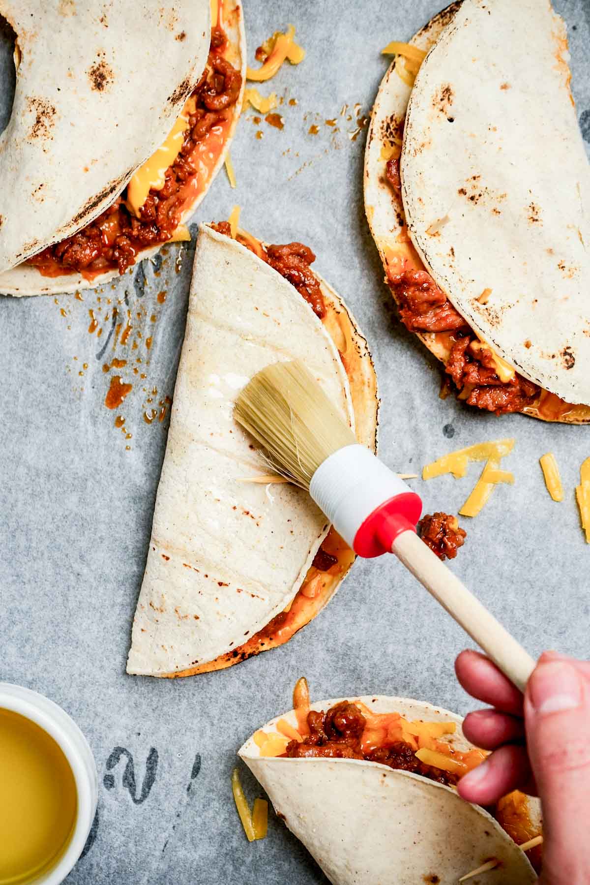 oil being brushed on a folder corn tortilla taco.