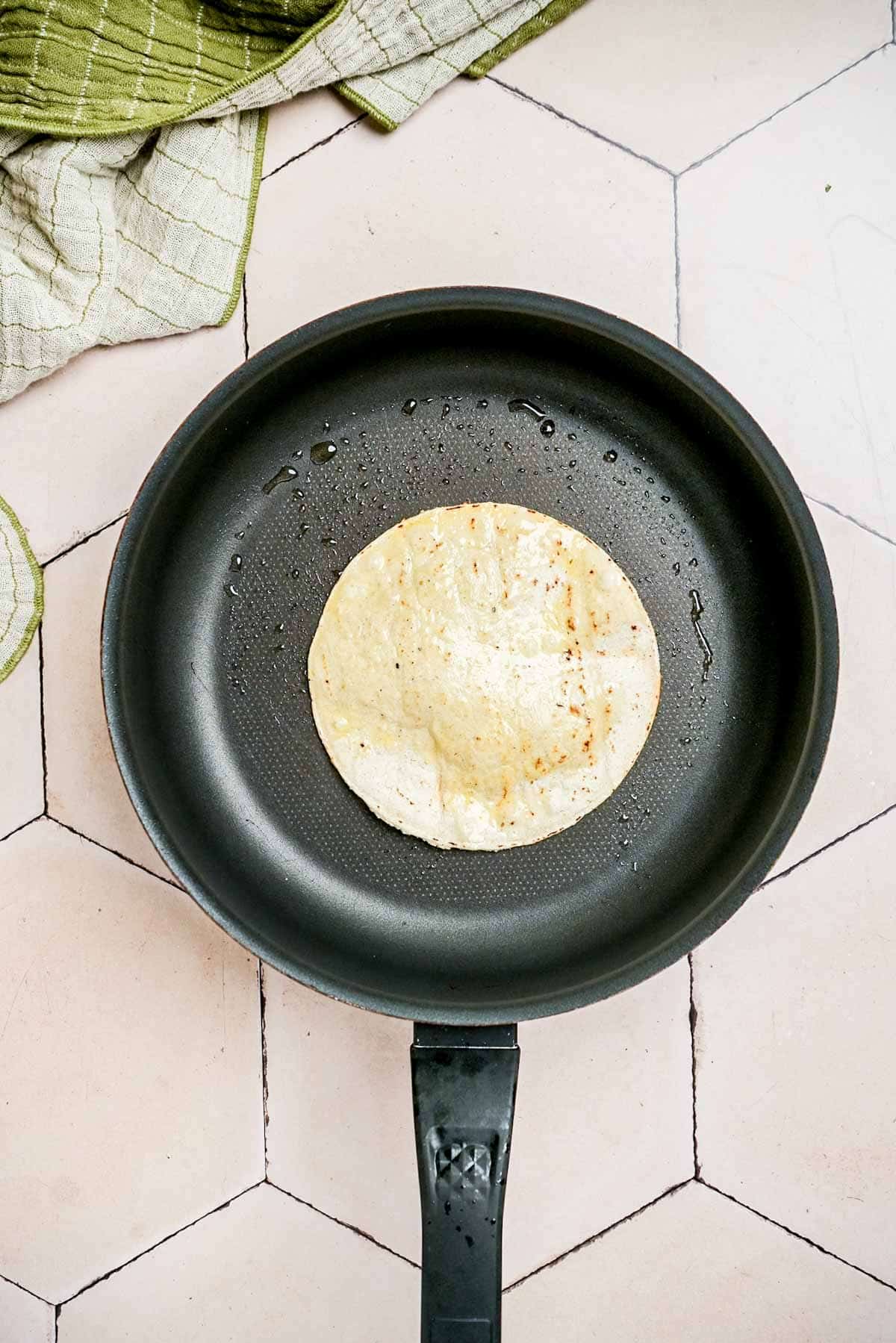 corn tortilla frying in a skillet.