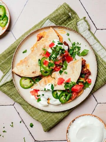 2 tacos on a plate with jalapenos and tomatoes.