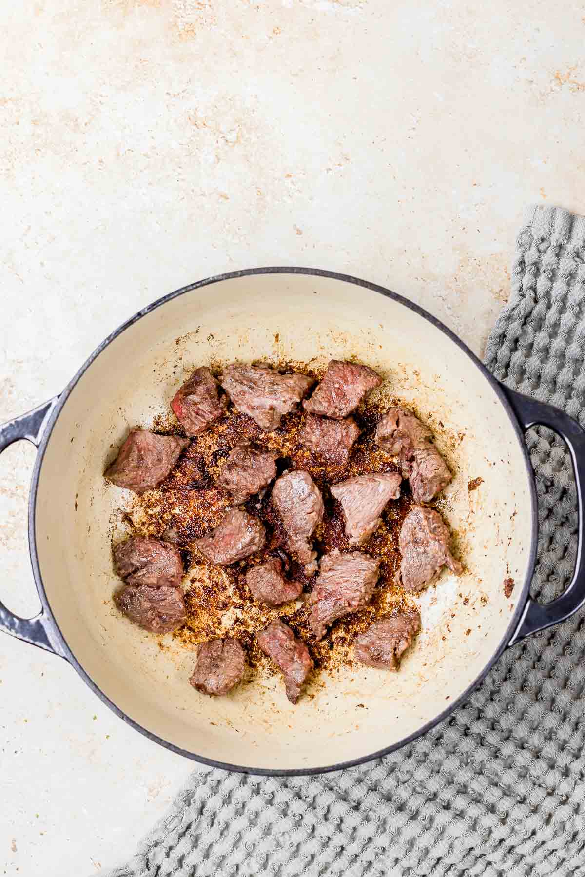 Beef cubes browning in a skillet.