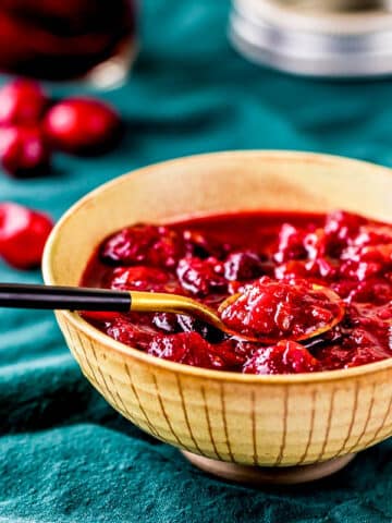 a bowl of cranberry orange chutney with a spoon.