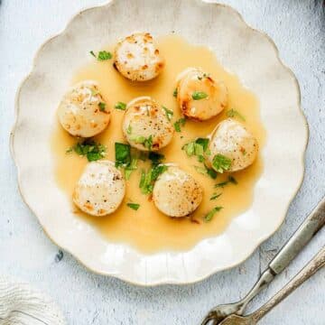 scallops on a plate with yellow sauce.