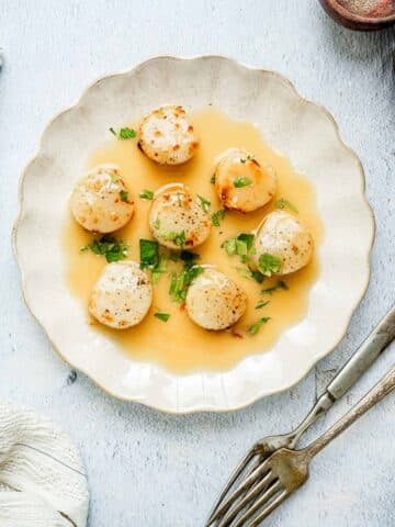 scallops on a plate with yellow sauce.