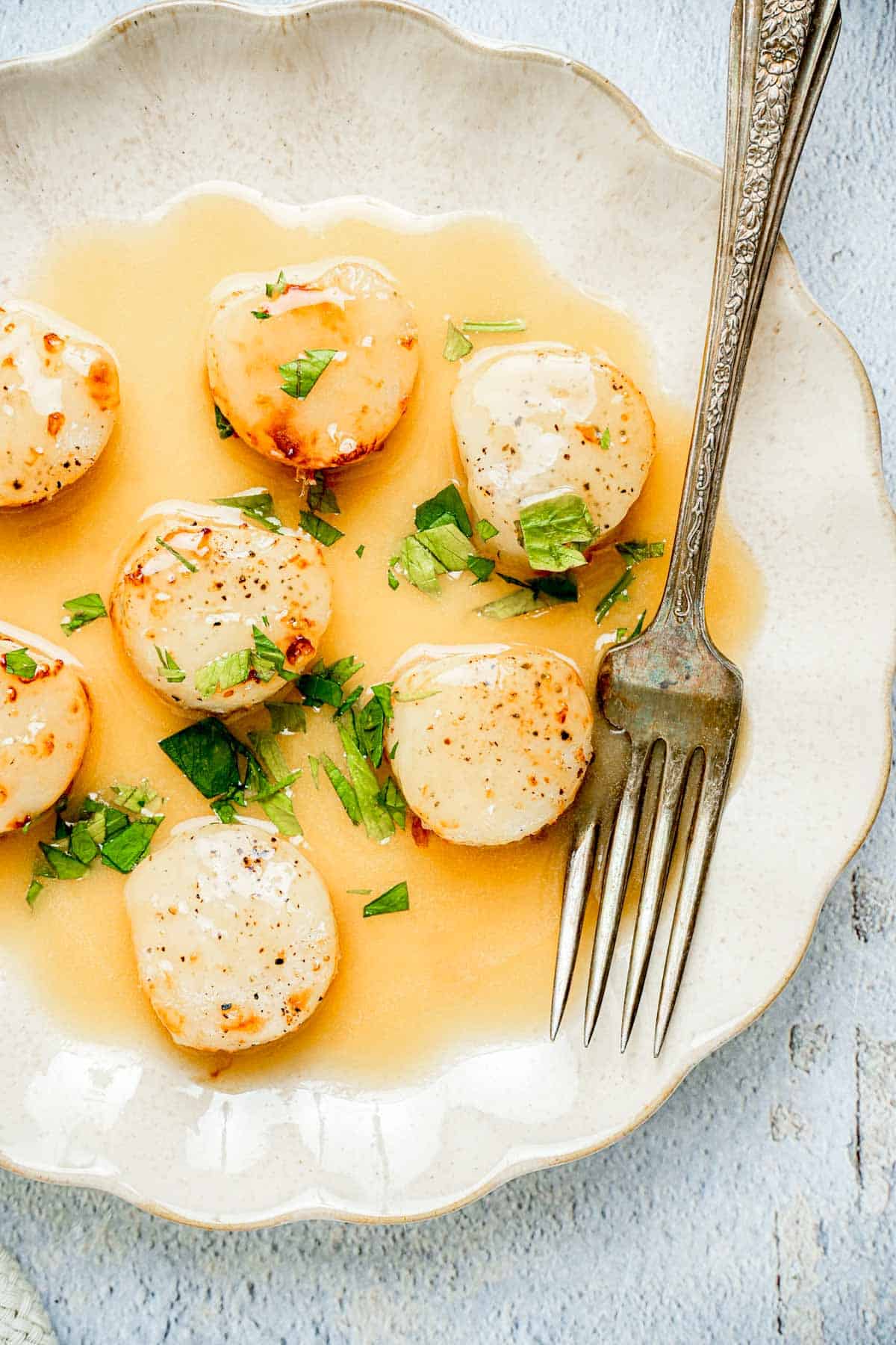 a plate of scallops in a butter sauce.