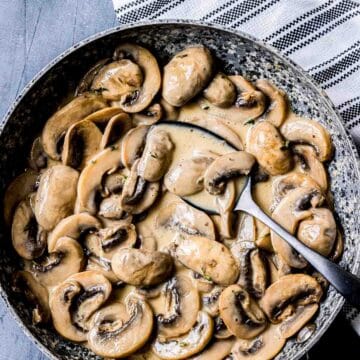 a bowl of creamy mushrooms wit a spoon.