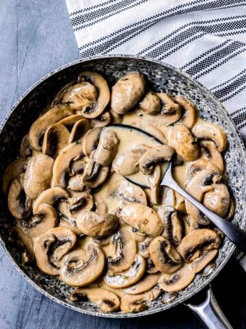 a bowl of creamy mushrooms wit a spoon.