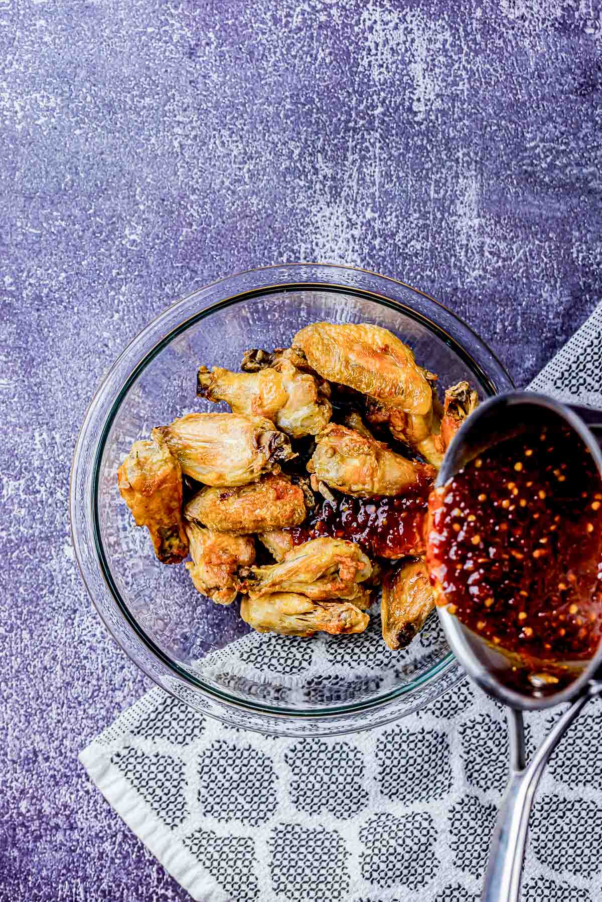 glaze being poured over top of the chicken wings.