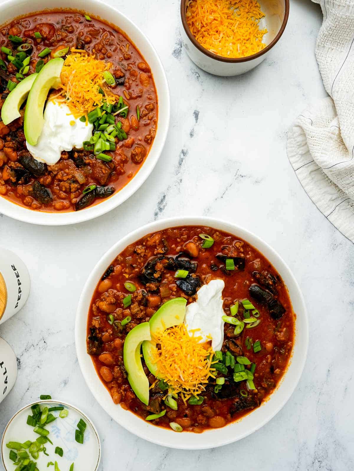 2 bowls of chili with avocado and sour cream.