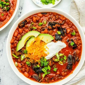 a bowls of red bean and beef chili with sour cream and green onions.