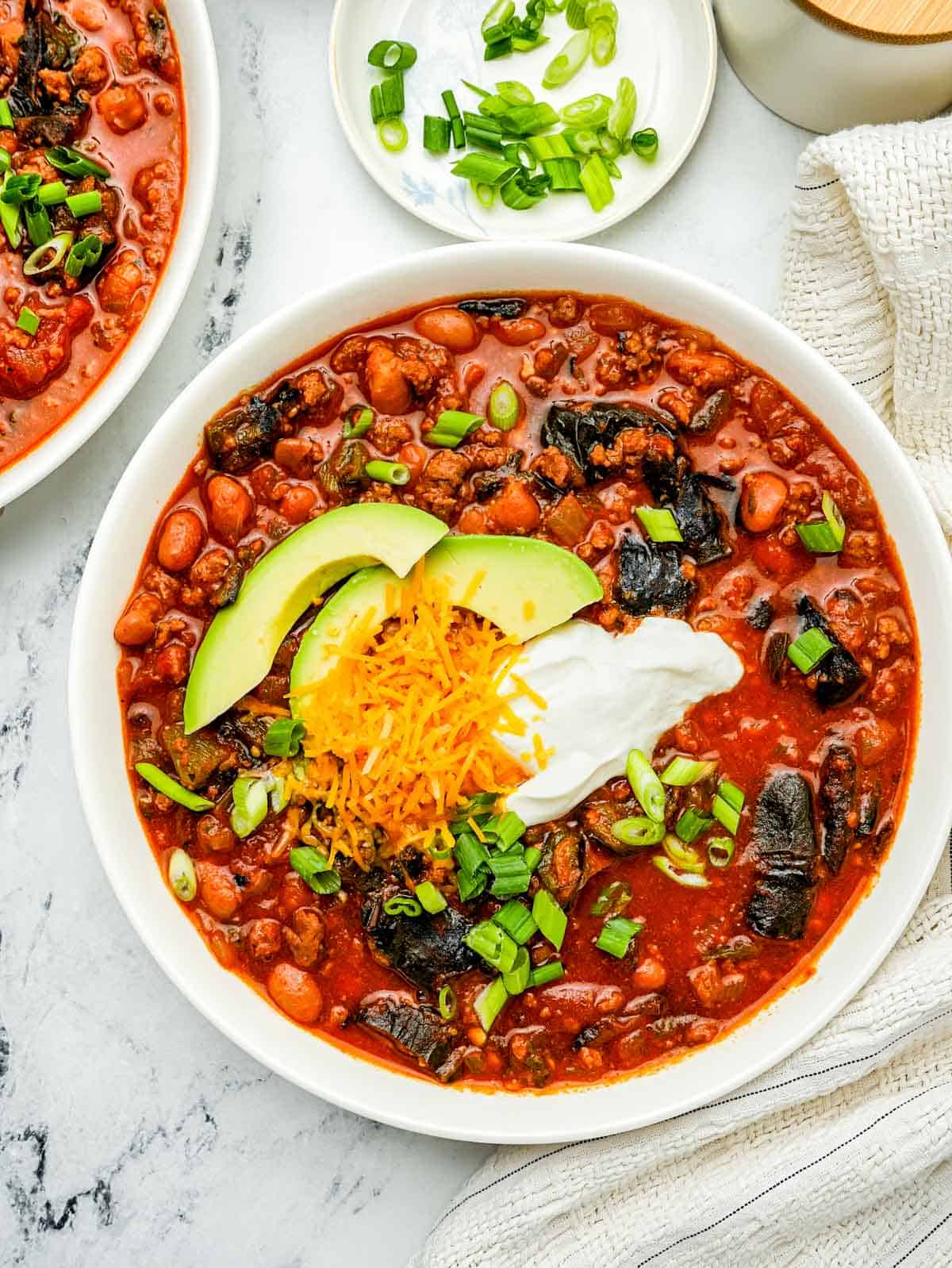 a bowls of red bean and beef chili with sour cream and green onions. 