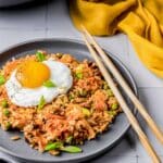 a plate of fried rice with a fried egg and chopsticks.