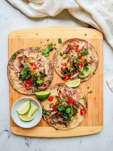 2 tacos on a wood board with toppings.