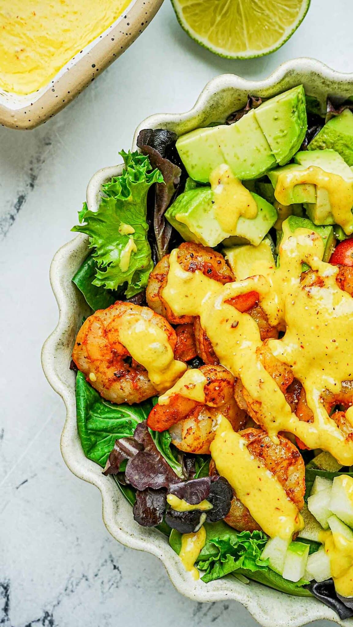 salad with shrimp, avocado and dressing on the top.