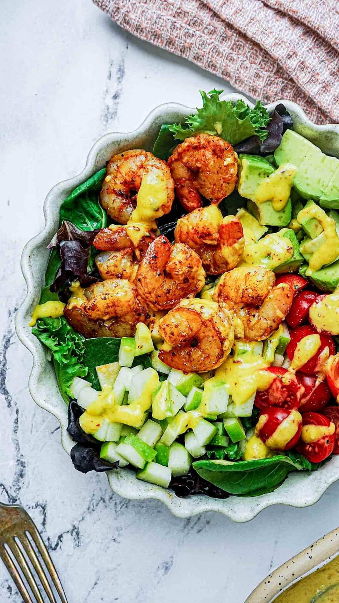 a salad of shrimp, peppers, lettuce and dressing in a bowl.