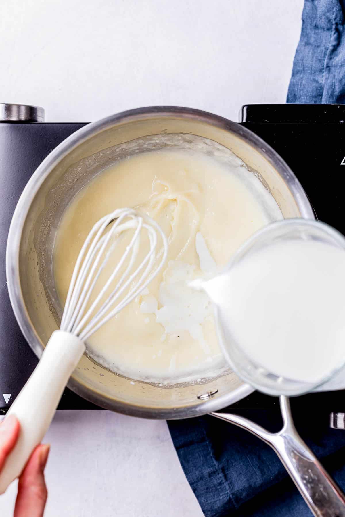 milk being poured into a saucepan.