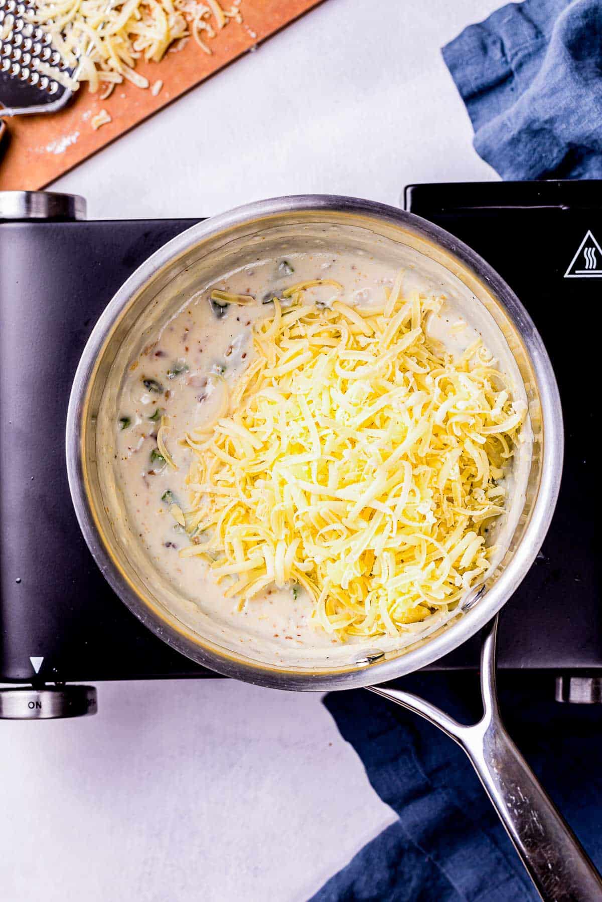 grated cheese added to a saucepan.