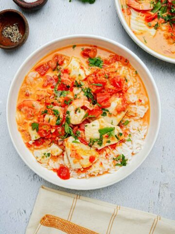 a bowl of tomato and fish soup with rice.